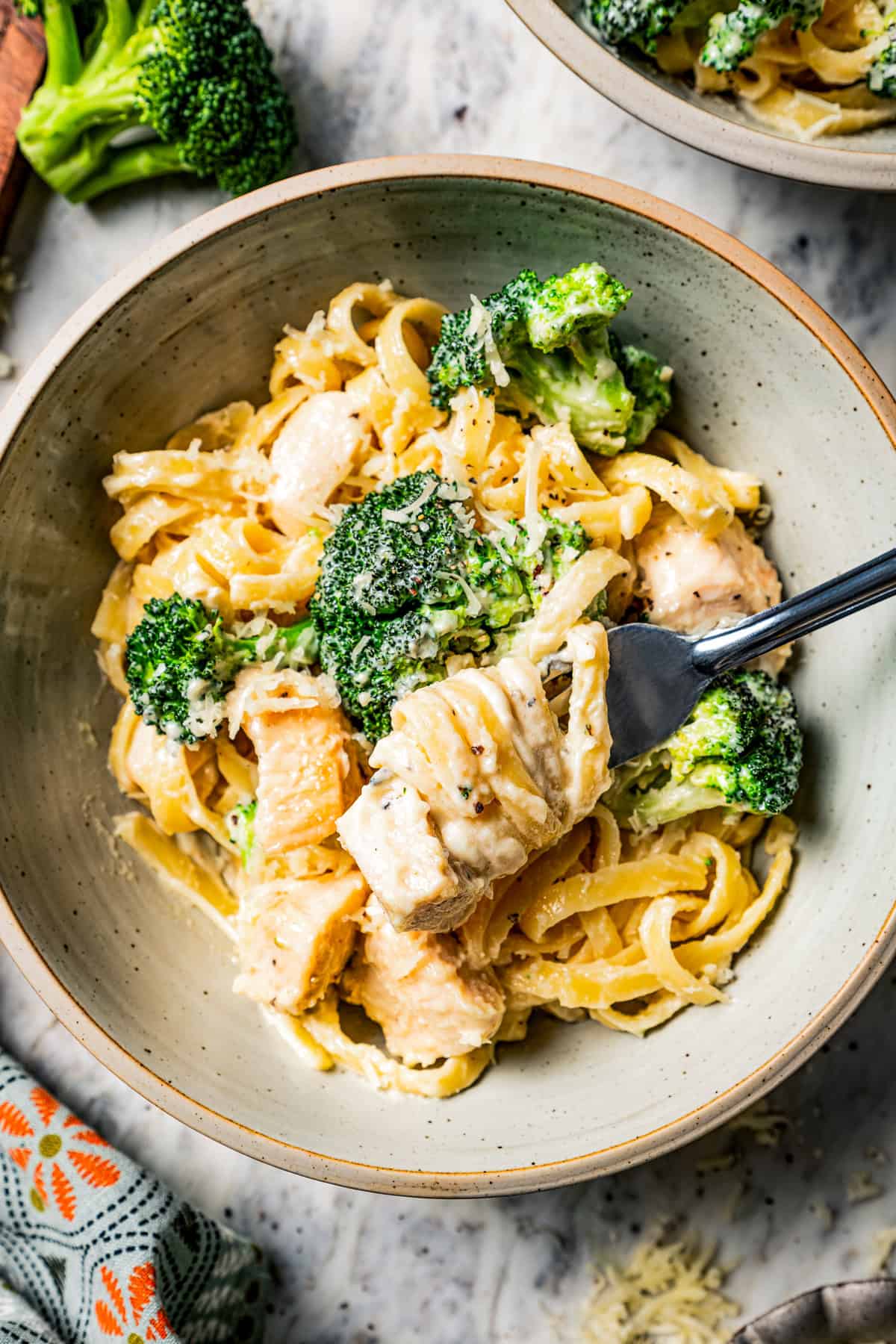 Serving of chicken fettuccine alfredo with broccoli in a bowl with a fork.