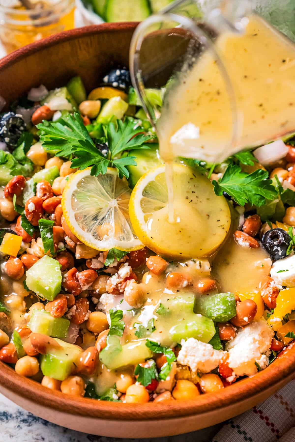 Pouring dressing over a salad with beans.