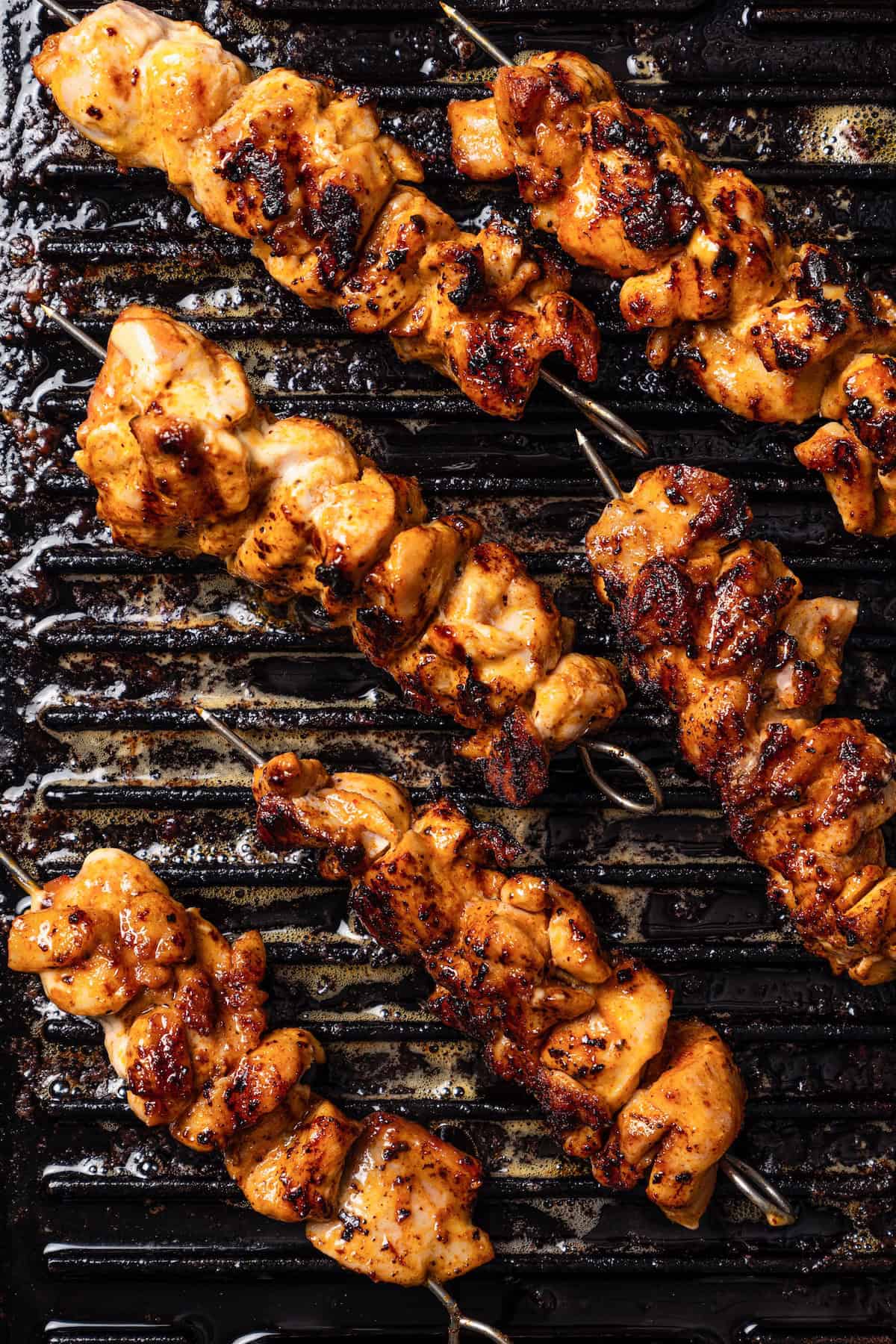 Bang bang chicken grilling on skewers.