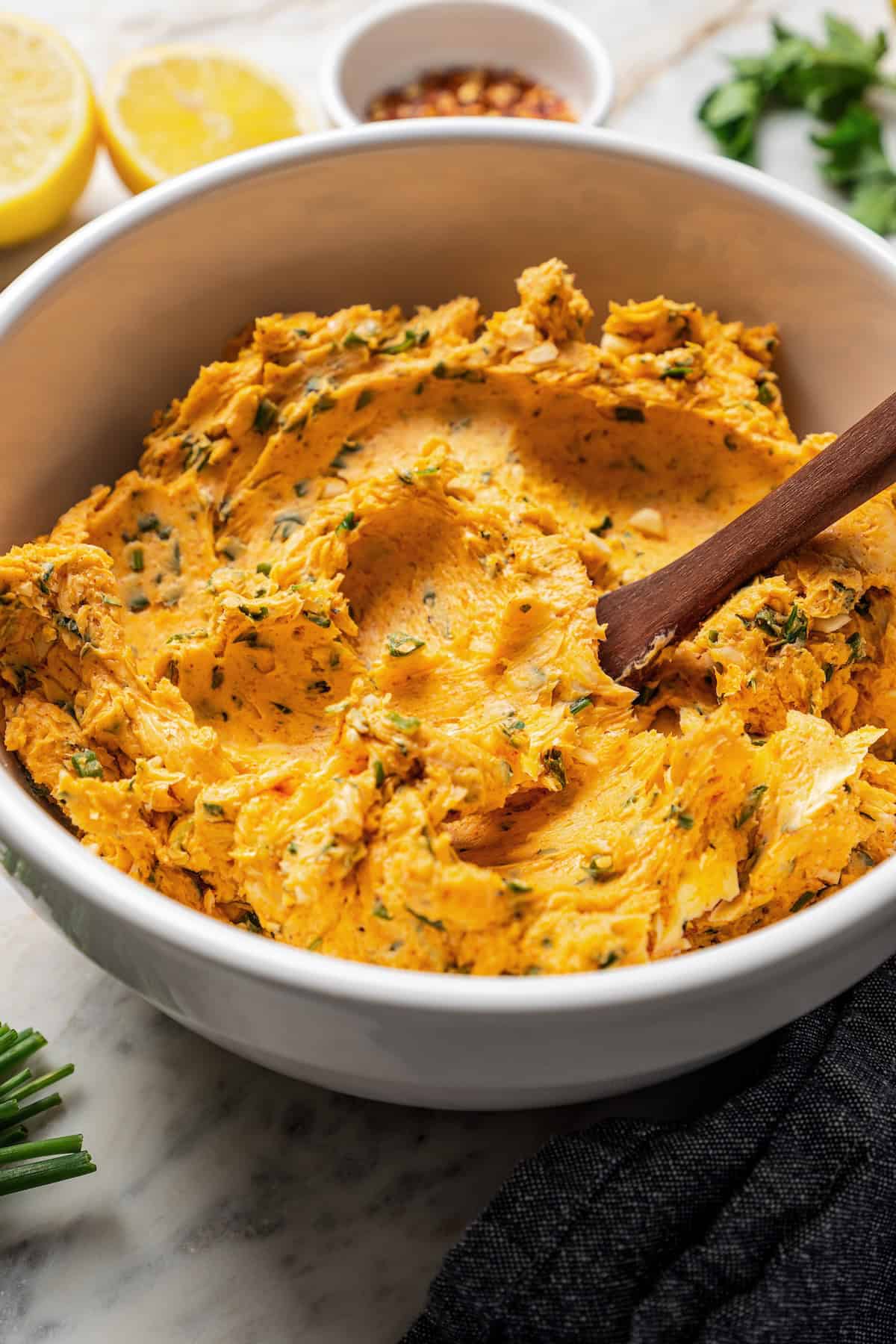 Cowboy butter in a white bowl with a wooden spatula.