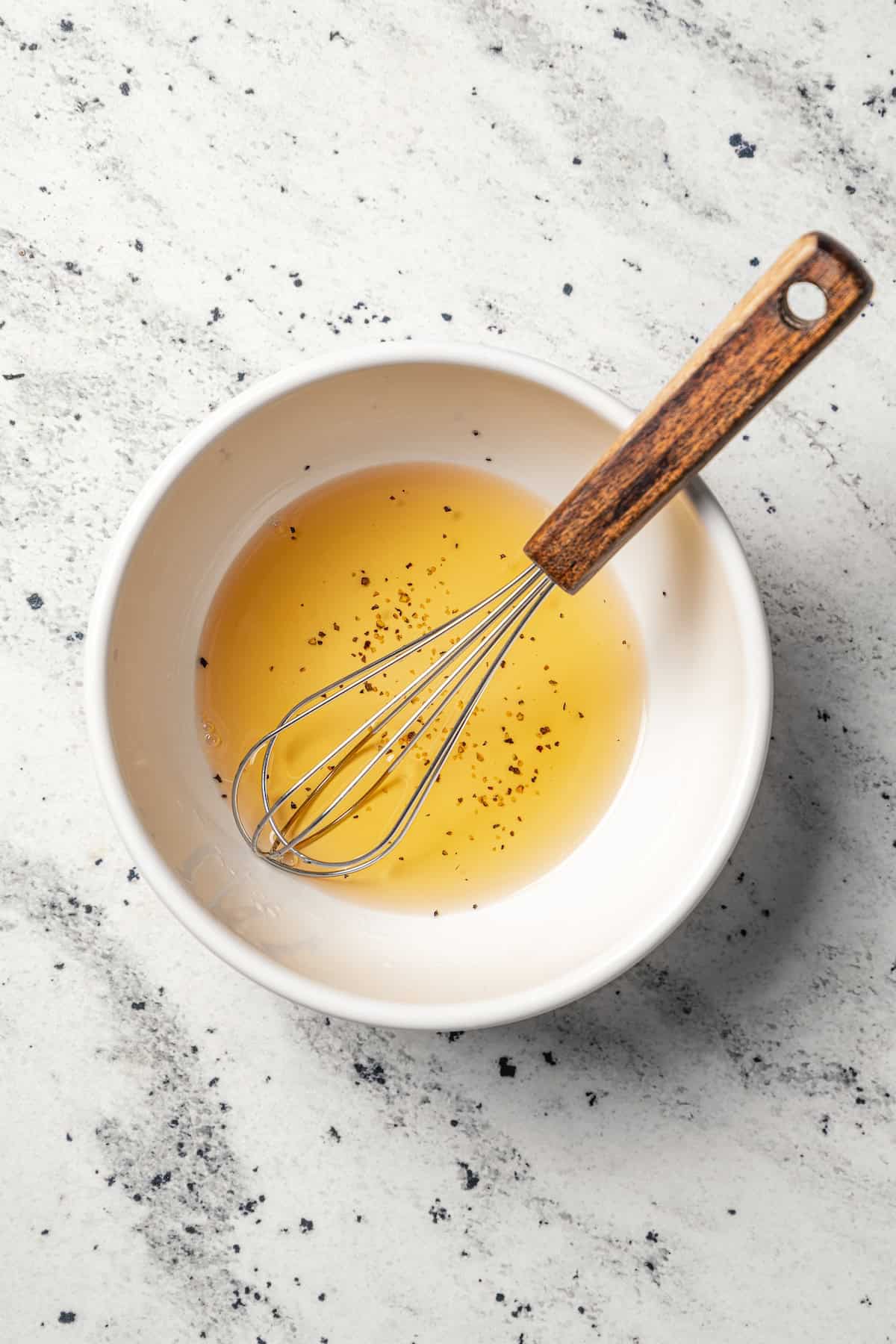 Salad dressing whisked in a white bowl.