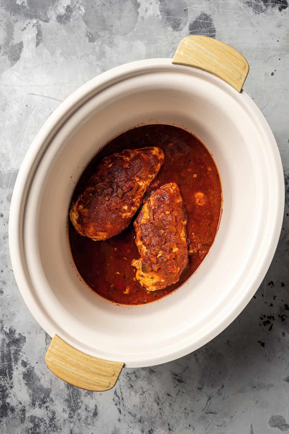 Cooked chicken breasts and sauce inside the crock pot.