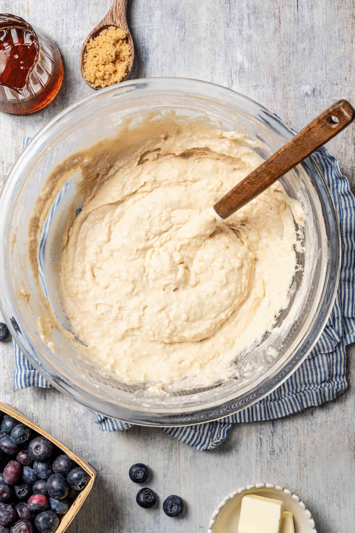 Pancake batter in a glass mixing bowl with a spoon.