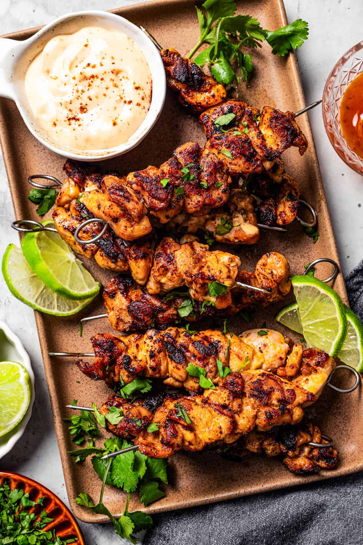 Chicken Skewers next to a bowl of dipping sauce on a baking sheet.