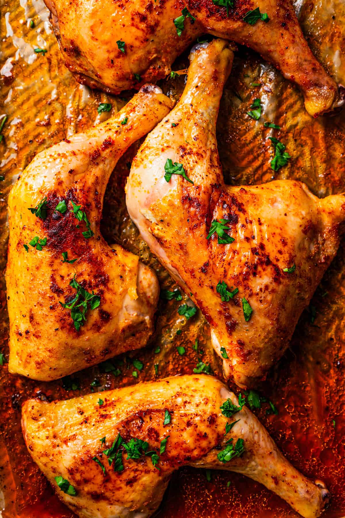 Roasted chicken leg quarters on a baking pan.