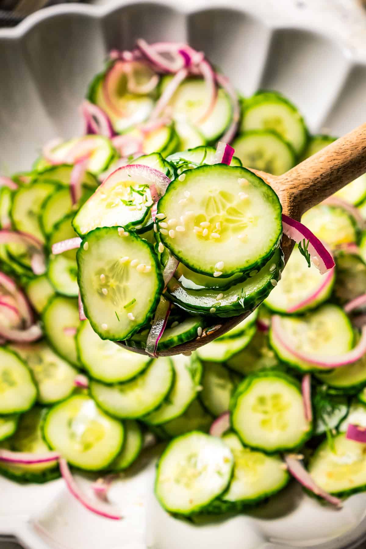 Scooping cucumber and onion salad from a bowl.