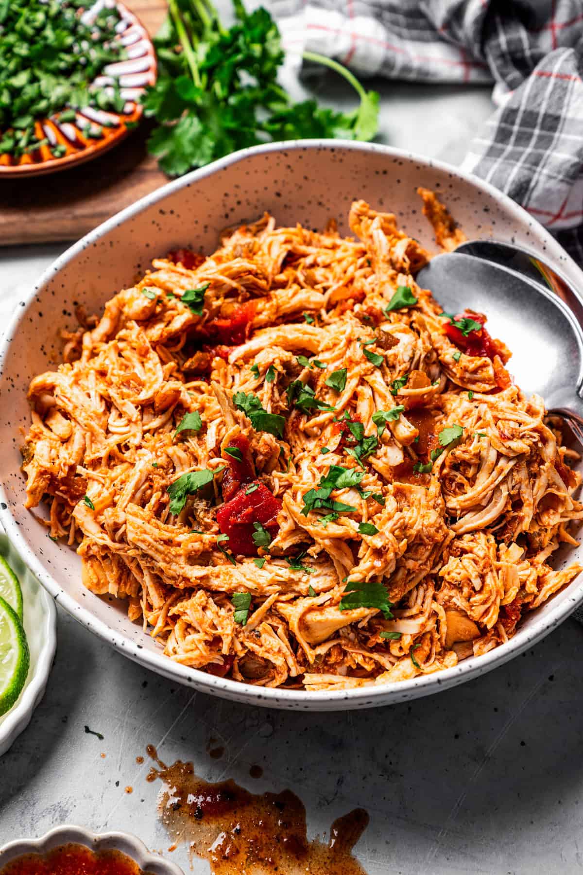 Pulled chicken in a large bowl with two serving spoons.