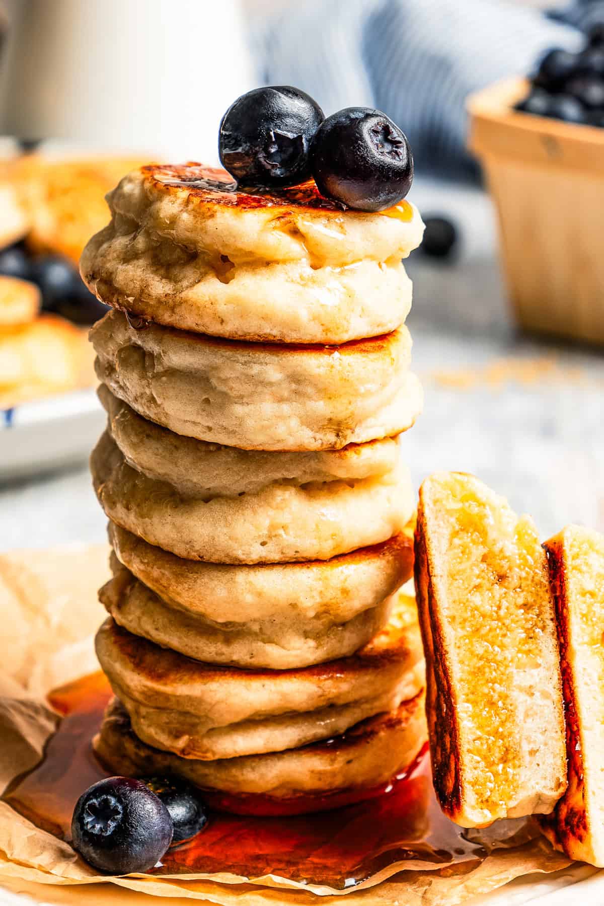 A close-up of a stack of silver dollar pancakes with syrup dripping on the sides of them.