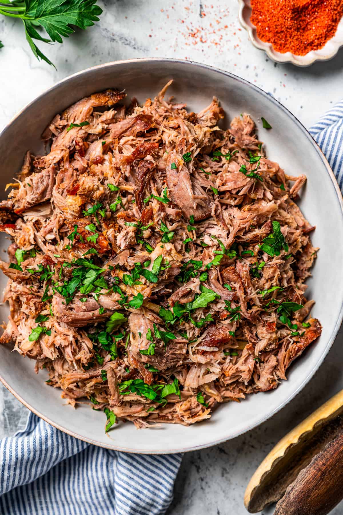 Kalua pork (Hawaiian pulled pork) is made from seasoned pork shoulder rubbed with sea salt and slow-roasted until it's fall-apart tender. Overhead view of shredded Kalua pork in a large serving bowl.