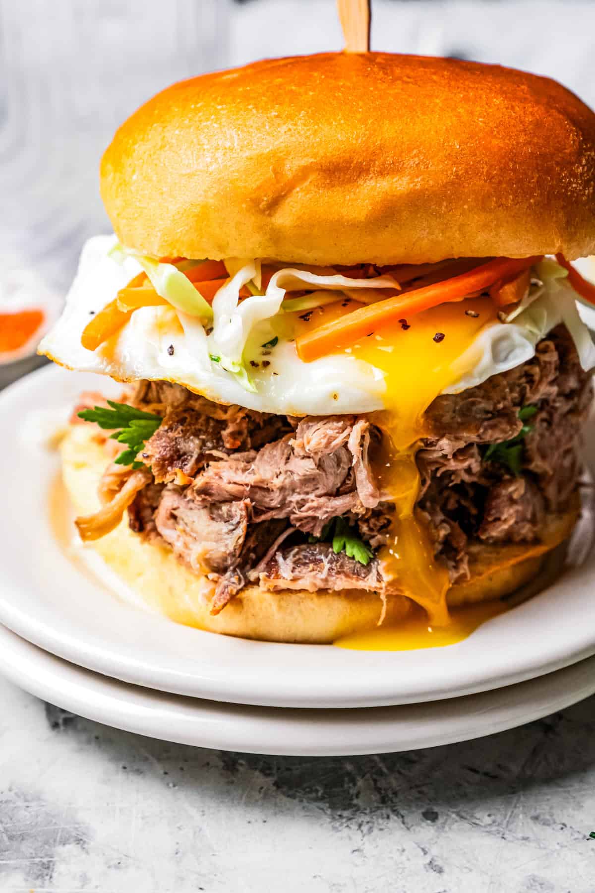 Kalua pork (Hawaiian pulled pork) is made from seasoned pork shoulder rubbed with sea salt and slow-roasted until it's fall-apart tender. Kalua pulled pork sandwich on a plate.