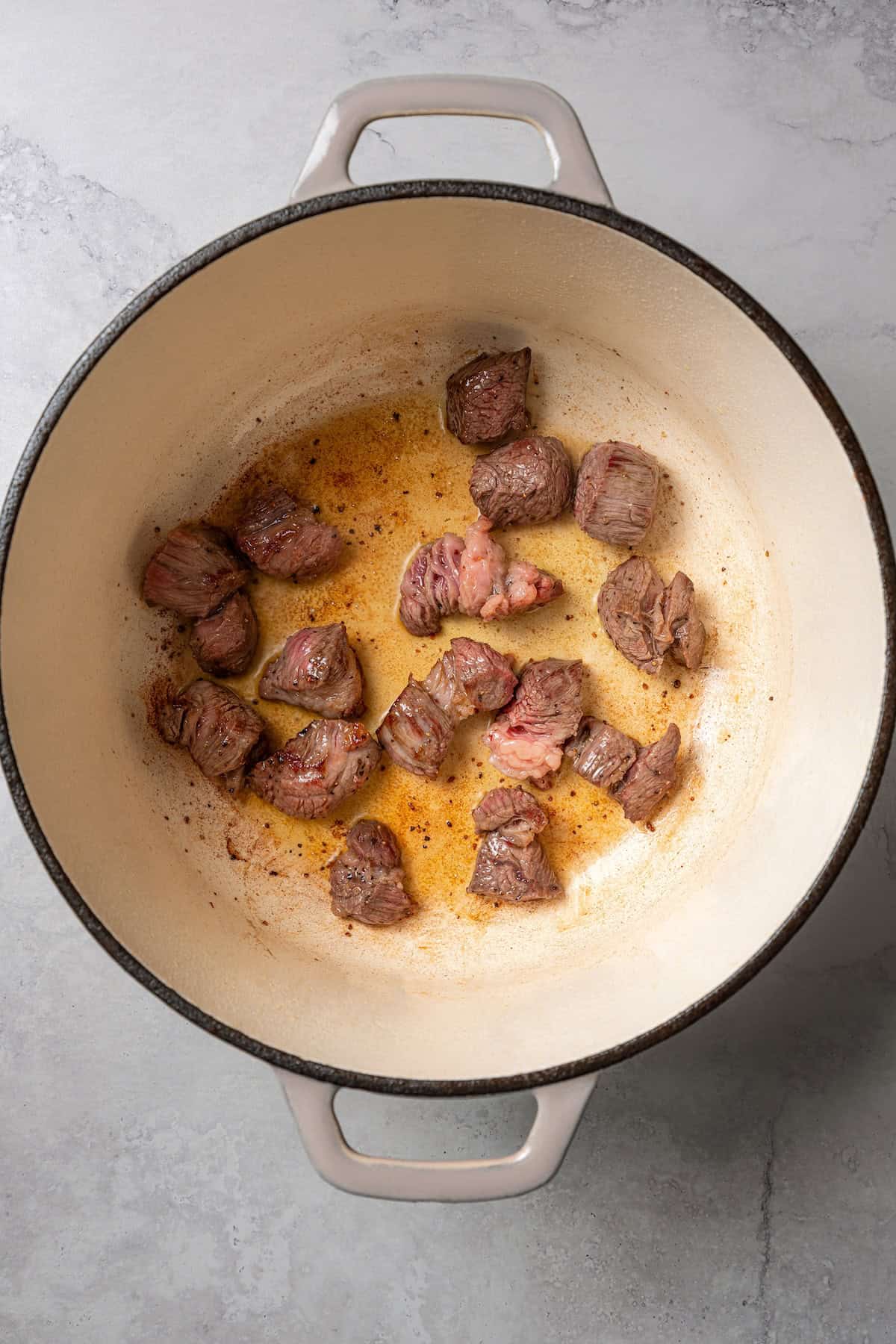 Seared beef cubes in a large pot.
