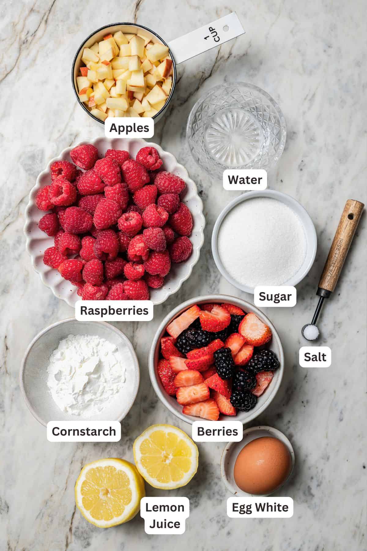 This easy mixed berry pie recipe combines three types of juicy berries with tender apples inside a light and flaky homemade pie crust. Berry pie ingredients with text labels overlaying each ingredient.