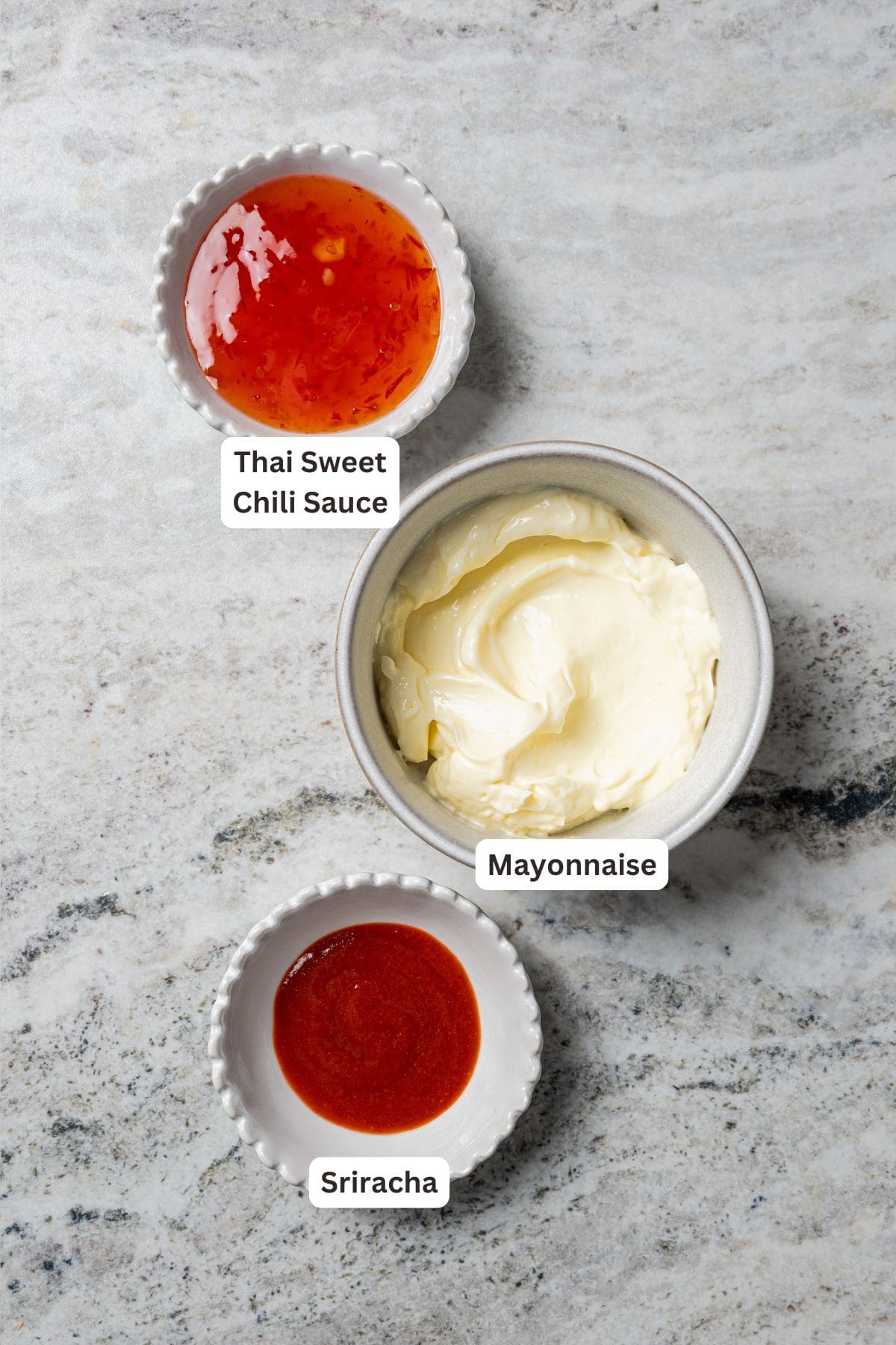 This easy coconut shrimp recipe makes crispy, golden-fried shrimp ready to dip in creamy sweet chili sauce. It's the best party appetizer! Spicy mayo dipping sauce ingredients with text labels overlaying each ingredient.