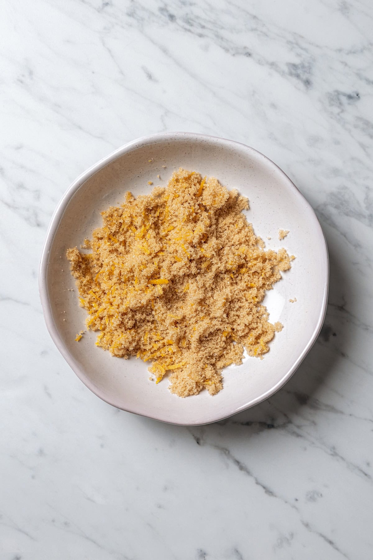 Massaged lemon zest and brown sugar in a bowl.