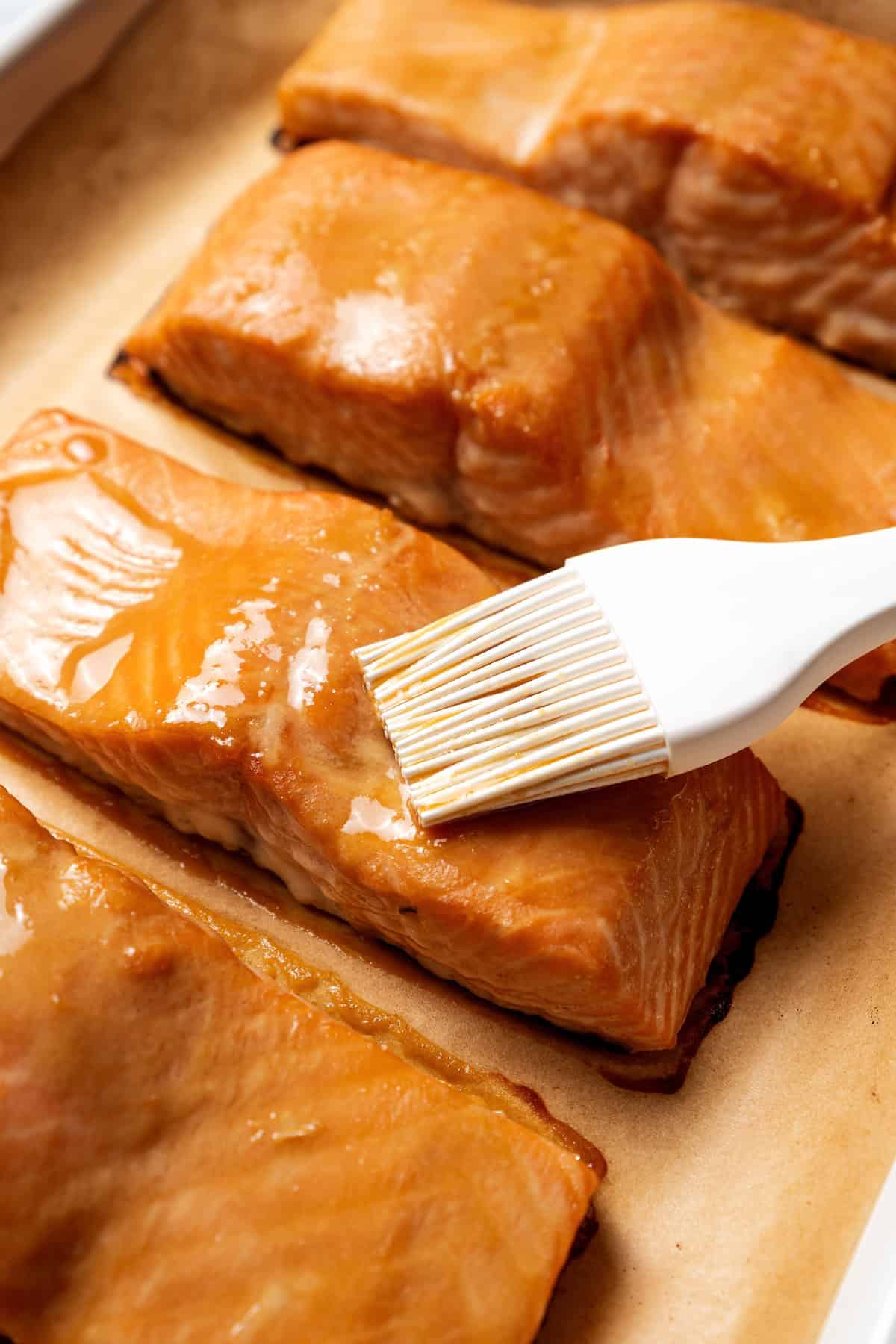This sweet and savory miso salmon is caramelized outside and tender and flaky inside. Serve it with rice for a quick, easy salmon dinner! A white basting brush coating salmon fillets with miso glaze on a baking sheet.