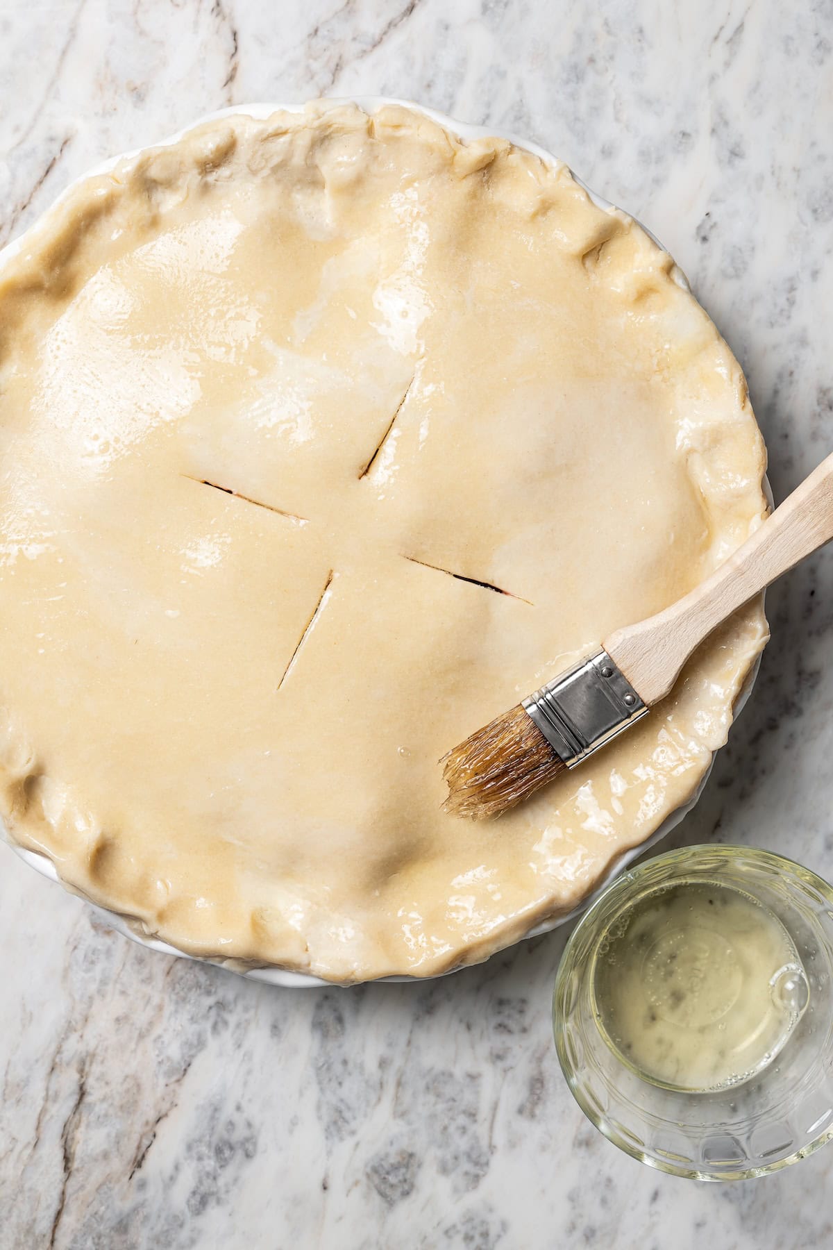 This easy mixed berry pie recipe combines three types of juicy berries with tender apples inside a light and flaky homemade pie crust. A basting brush coating the top crust of a pie with egg wash.