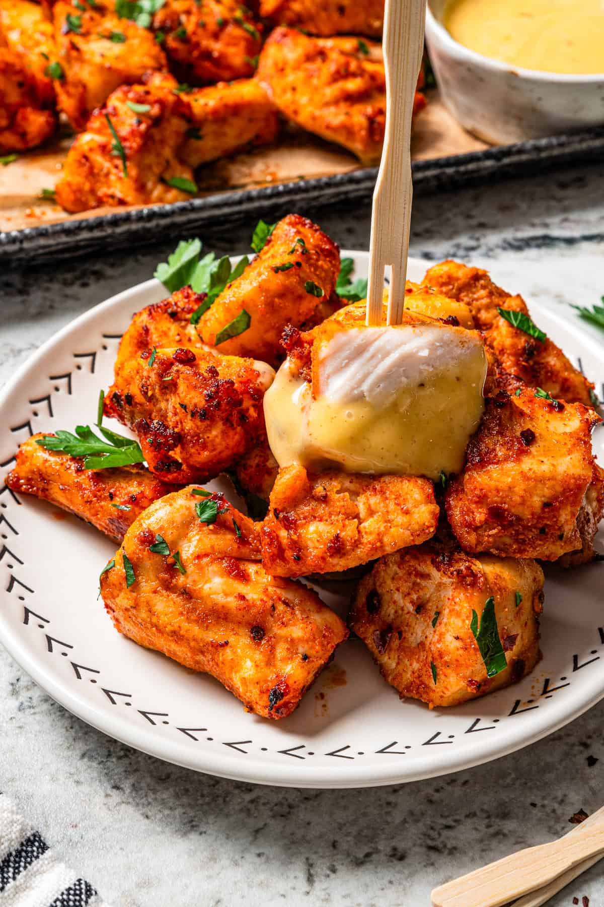 Make crispy air fryer chicken bites in just 15 minutes! Pair these juicy bites with your favorite dipping sauce for an easy meal or appetizer. Air fried chicken bites served on a plate, with a cocktail skewer stuck into the top piece.