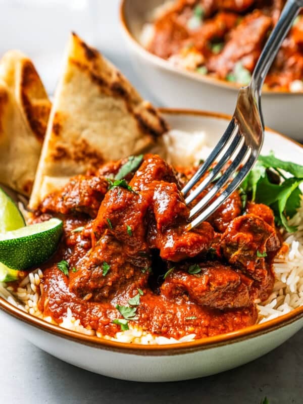 Beef madras curry served over a bowl of rice with a side of naan bread.