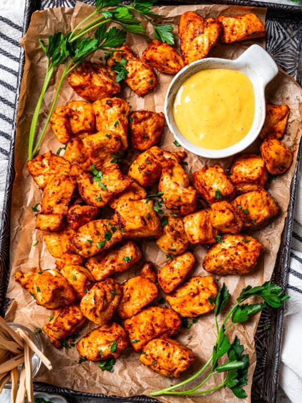 Air fried chicken bites are served on a tray next to a bowl of honey mustard sauce.