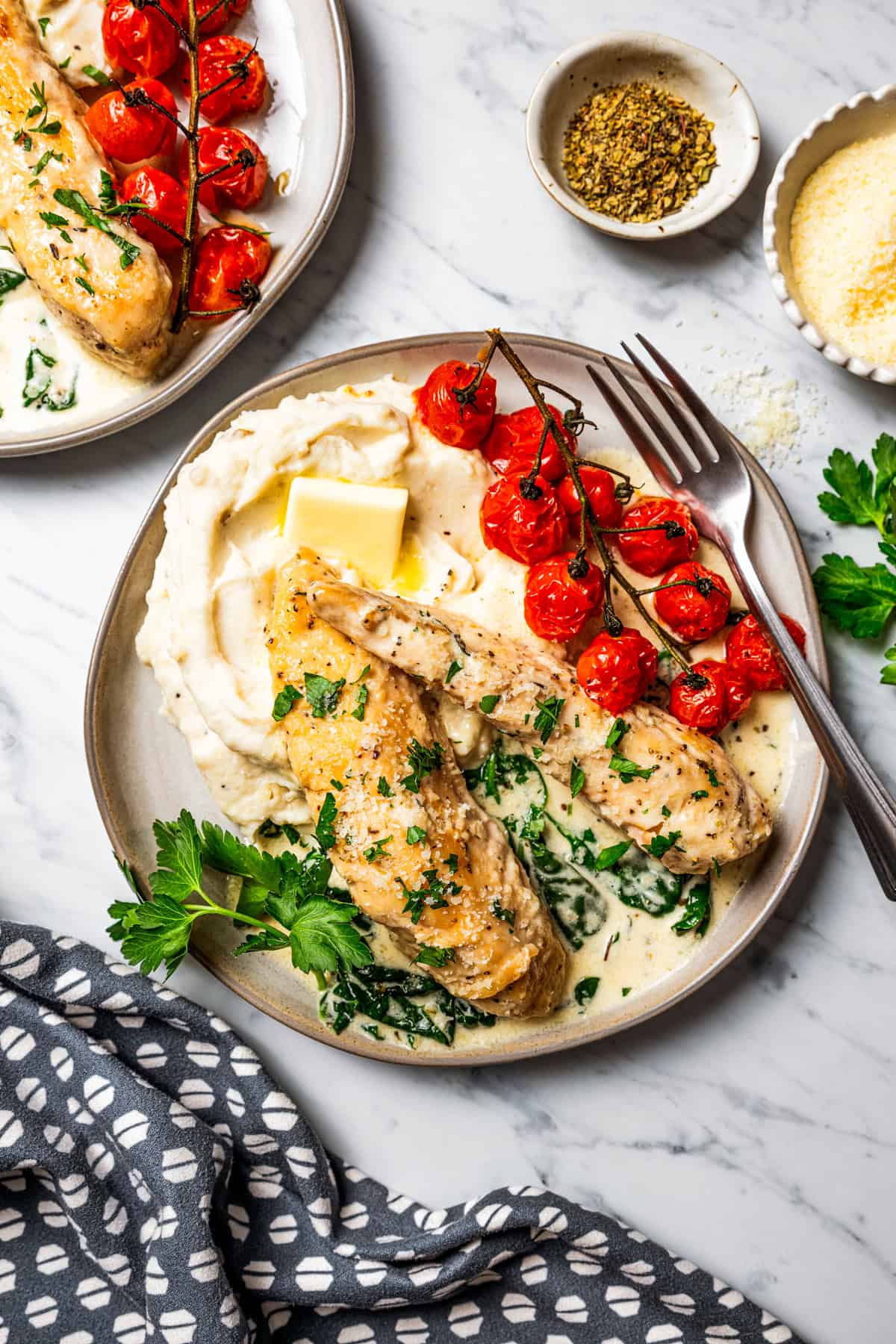 Creamy chicken Florentine is a one-pan dinner with golden-fried chicken smothered in a garlicky spinach cream sauce. Make it in 30 minutes! Chicken Florentine served over mashed potatoes on a plate with a side of blistered vine tomatoes.