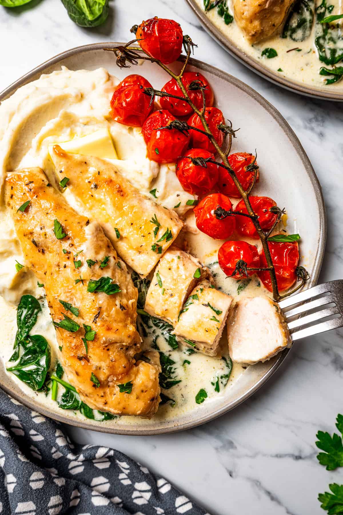 Creamy chicken Florentine is a one-pan dinner with golden-fried chicken smothered in a garlicky spinach cream sauce. Make it in 30 minutes! Sliced chicken florentine served on a plate with mashed potatoes and cherry tomatoes on a vine.