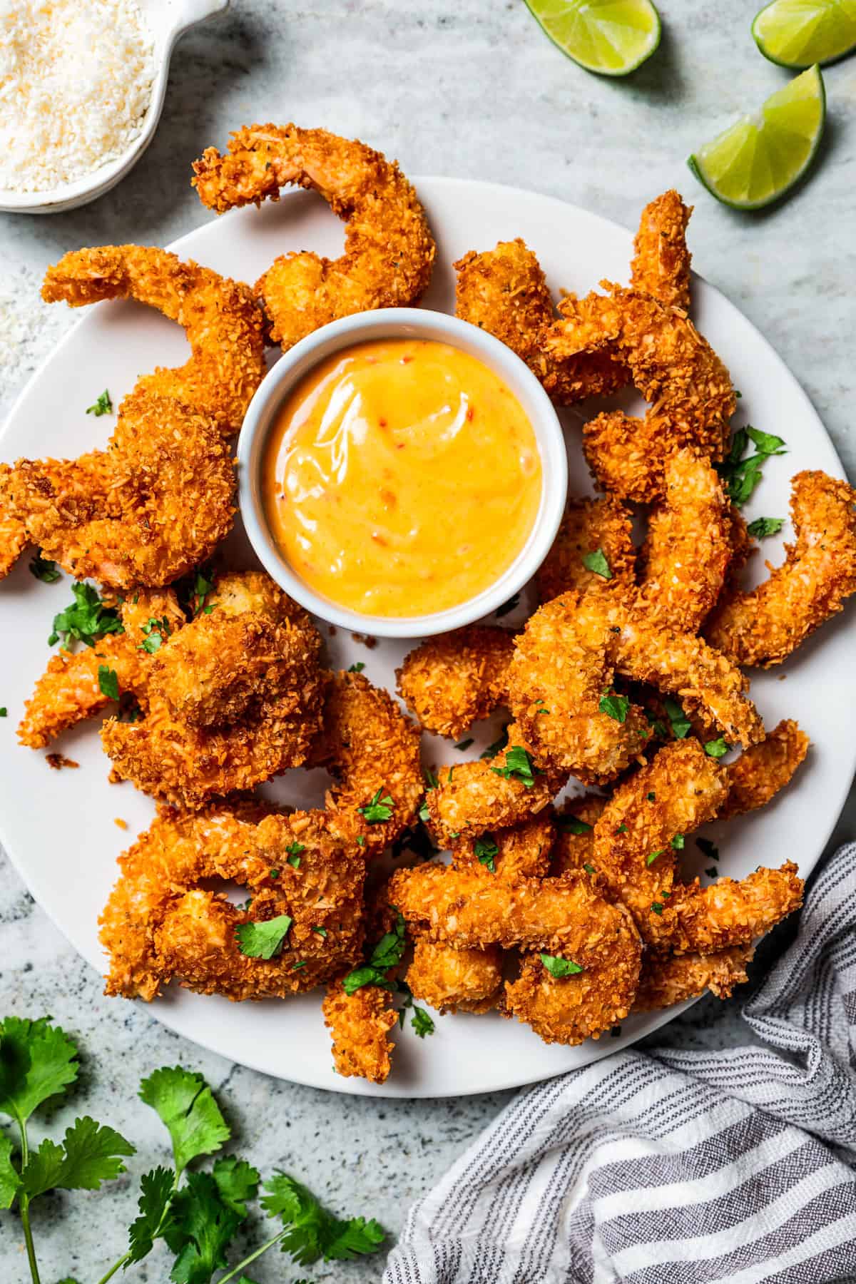This easy coconut shrimp recipe makes crispy, golden-fried shrimp ready to dip in creamy sweet chili sauce. It's the best party appetizer! A platter of Coconut shrimp with a dipping sauce.