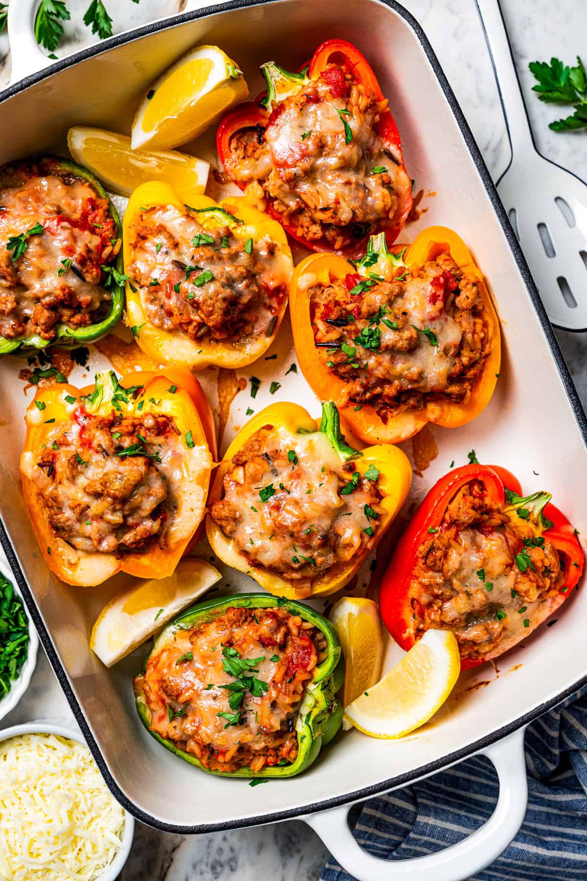 Esses pimentões recheados de peru moídos clássicos estão repletos de carne moída temperada, arroz selvagem e tomate suculento, coberto com queijo derretido e assado. Pimentão recheado de peru moído organizado em uma assadeira por dieethood.com