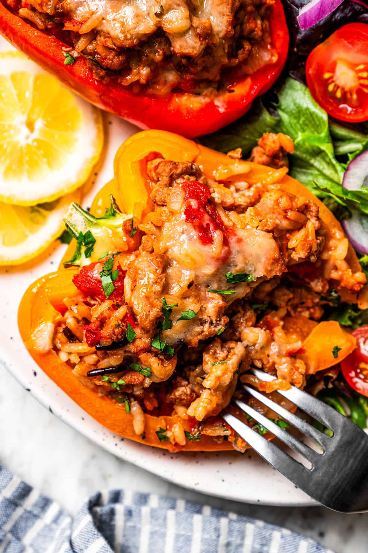 Esses pimentões recheados de peru moídos clássicos estão repletos de carne moída temperada, arroz selvagem e tomate suculento, coberto com queijo derretido e assado. Um garfo em uma pimenta de pelúcia.