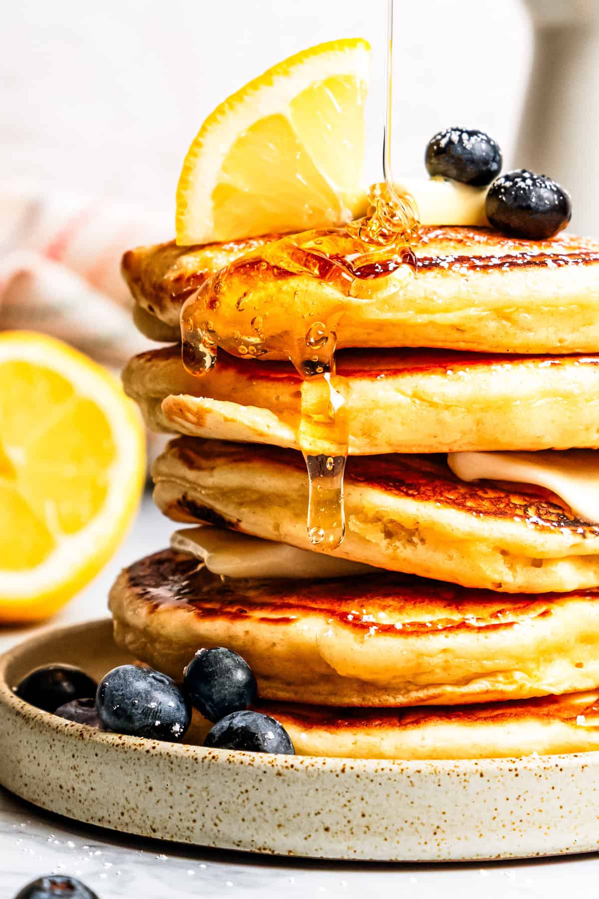 Melt-in-your-mouth lemon ricotta pancakes are the best brunch! They're light, fluffy, and bursting with bright, fresh lemon zest and juice. Syrup dripping down a stack of pancakes.