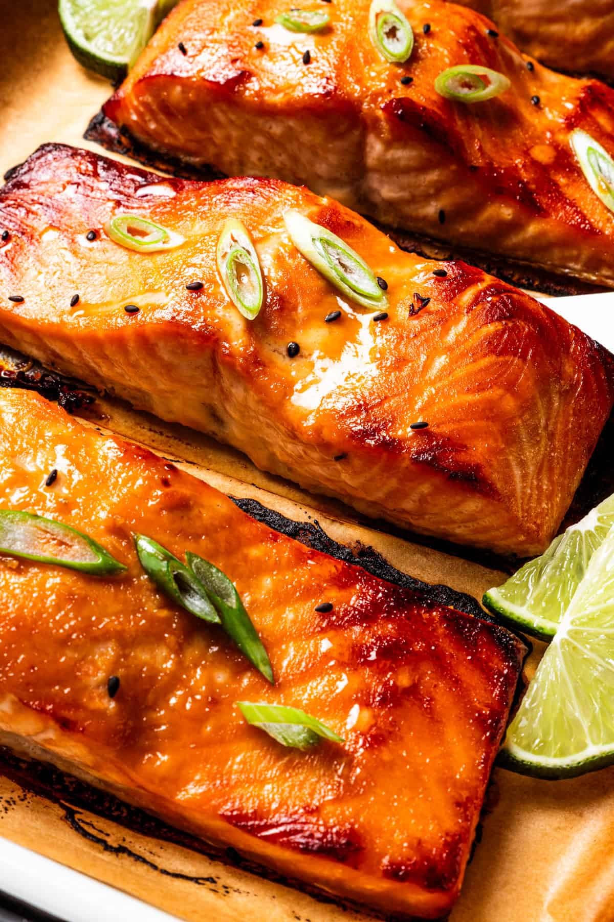 This sweet and savory miso salmon is caramelized outside and tender and flaky inside. Serve it with rice for a quick, easy salmon dinner! Close shot of miso salmon garnished with sesame seeds and scallions on a lined baking tray.