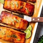 Miso salmon on a lined baking tray, with a spatula tucked under one of the fillets.