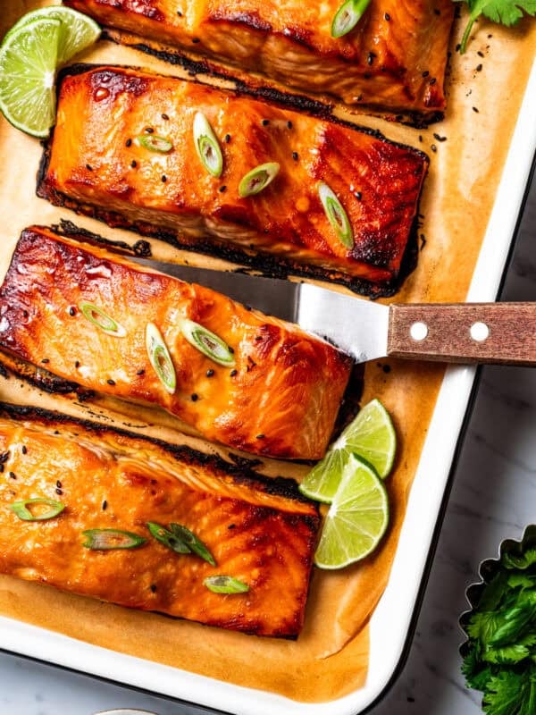 Miso salmon on a lined baking tray, with a spatula tucked under one of the fillets.