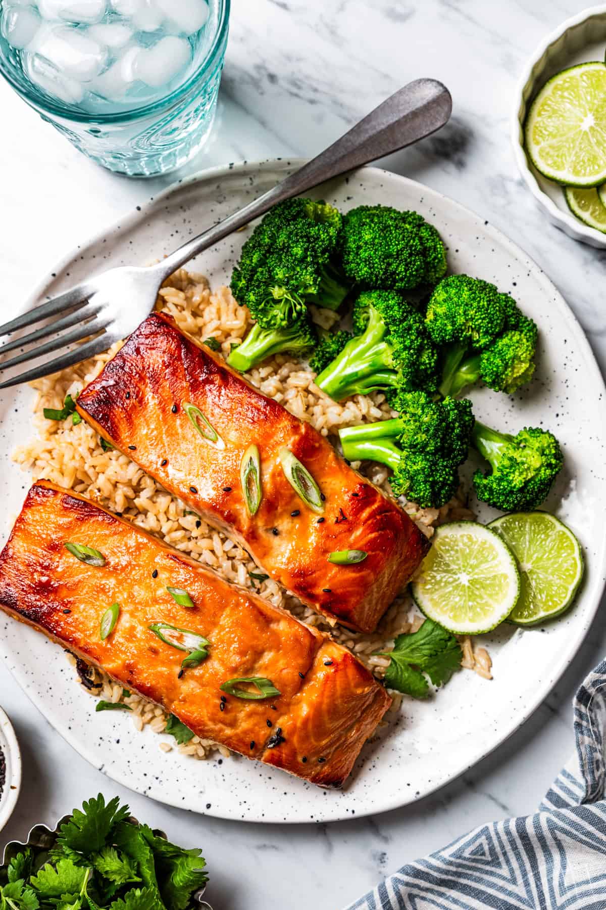 This sweet and savory miso salmon is caramelized outside and tender and flaky inside. Serve it with rice for a quick, easy salmon dinner! Two miso salmon fillets served over rice with a side of steamed broccoli on a plate with a fork.