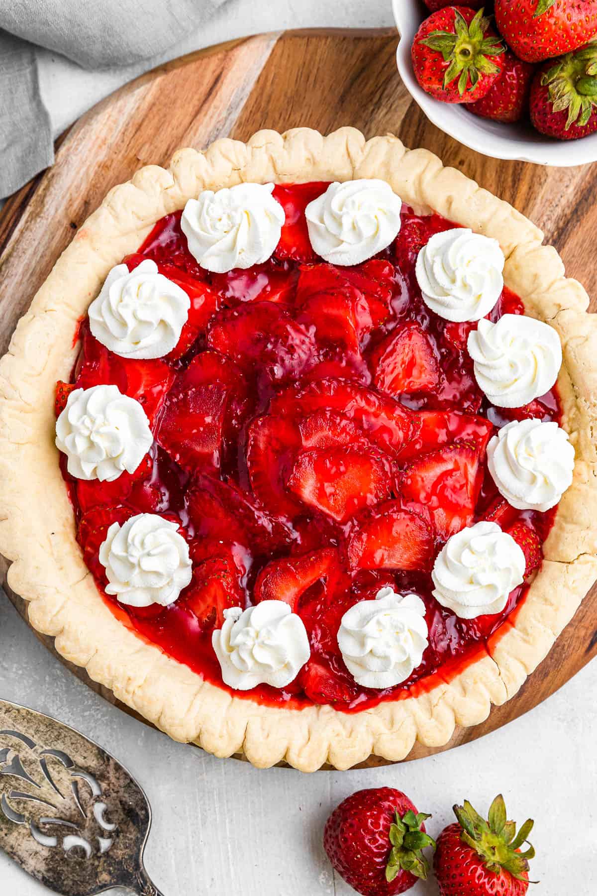 Full homemade strawberry pie topped with mounds of whipped cream.
