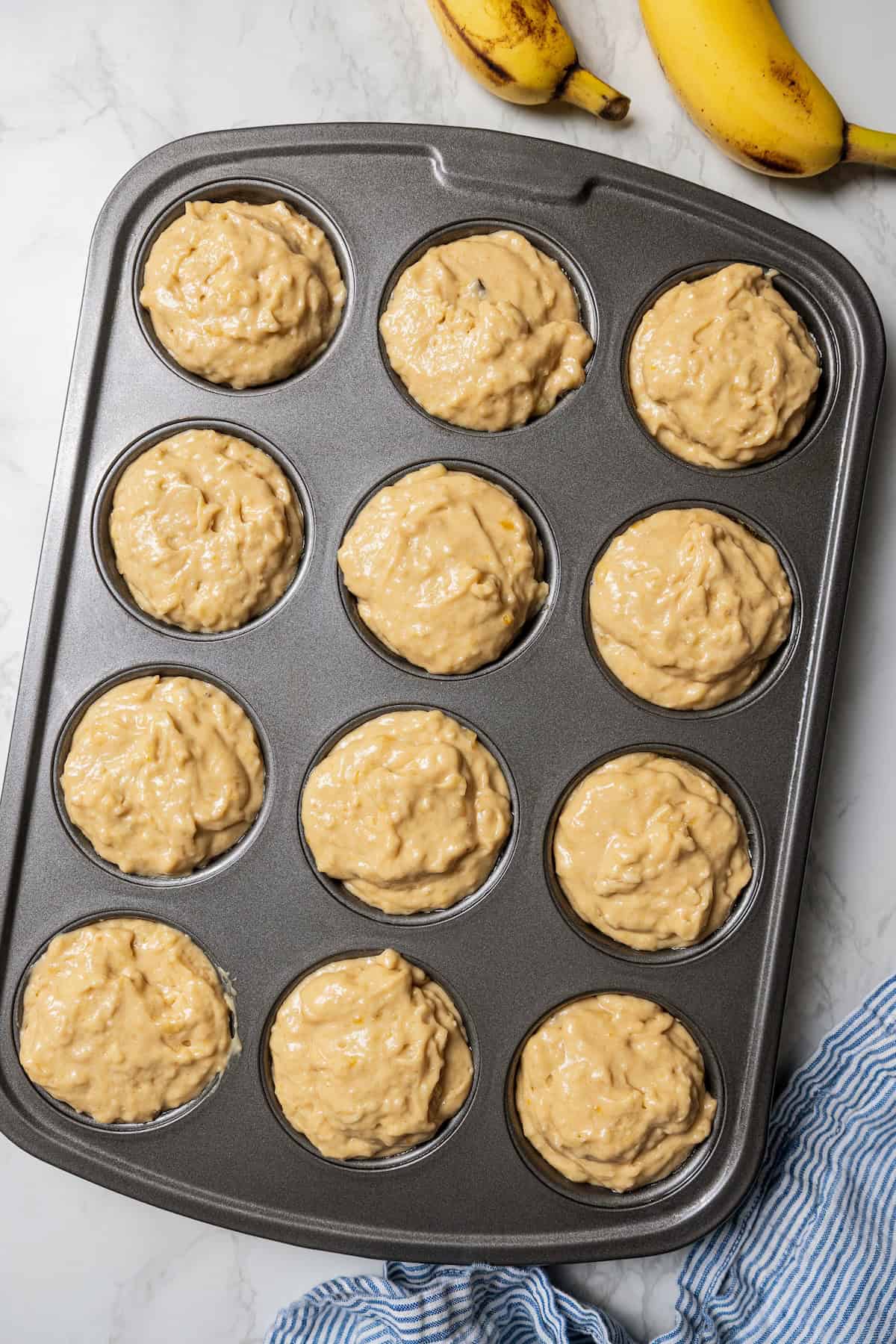 These soft, buttery banana bread muffins are easy to make with maple syrup, brown sugar, and cinnamon. It's impossible to eat just one! Banana bread muffin batter in a muffin pan.