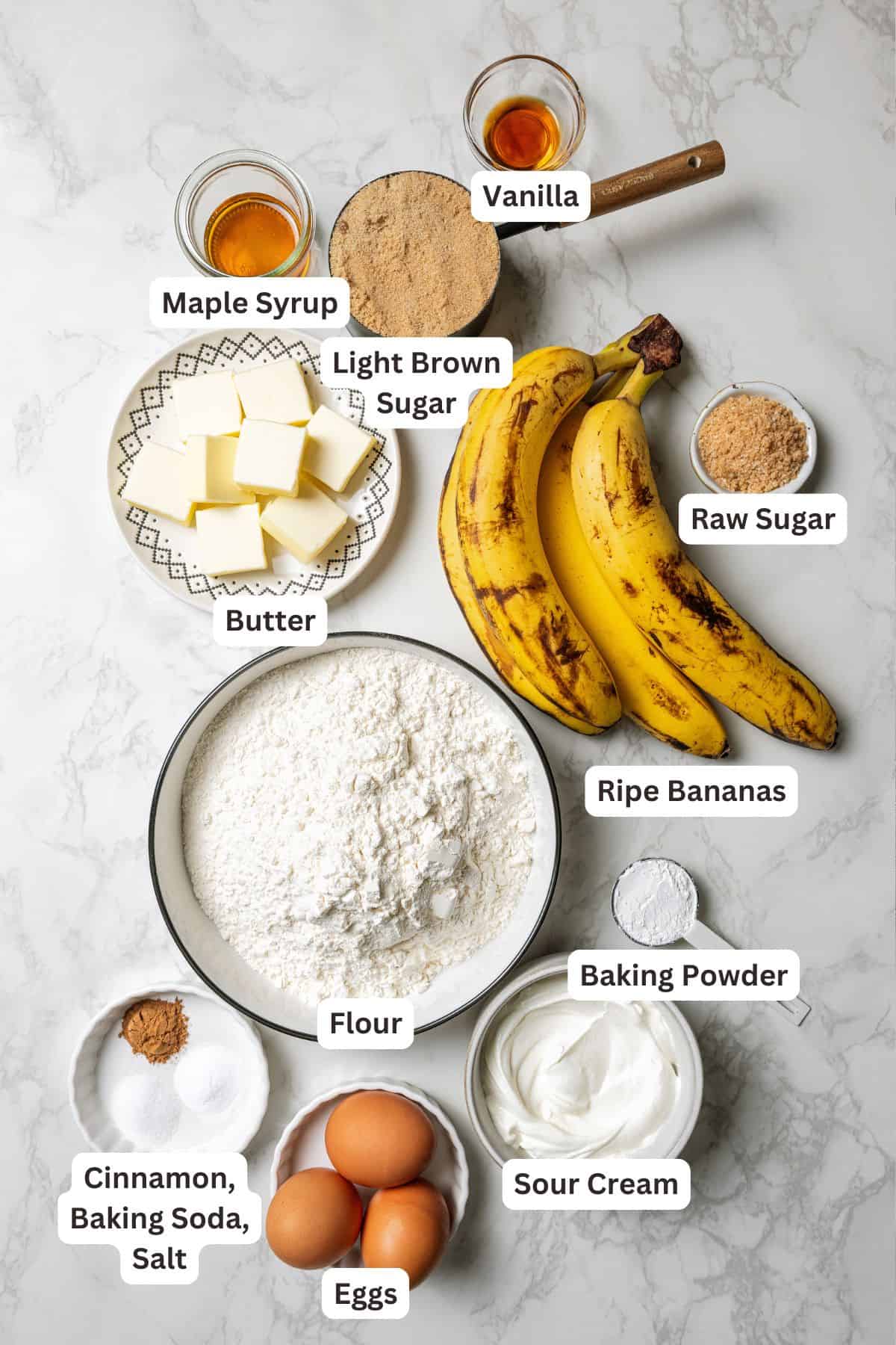 These soft, buttery banana bread muffins are easy to make with maple syrup, brown sugar, and cinnamon. It's impossible to eat just one! Banana bread muffins ingredients with text labels overlaying each ingredient.