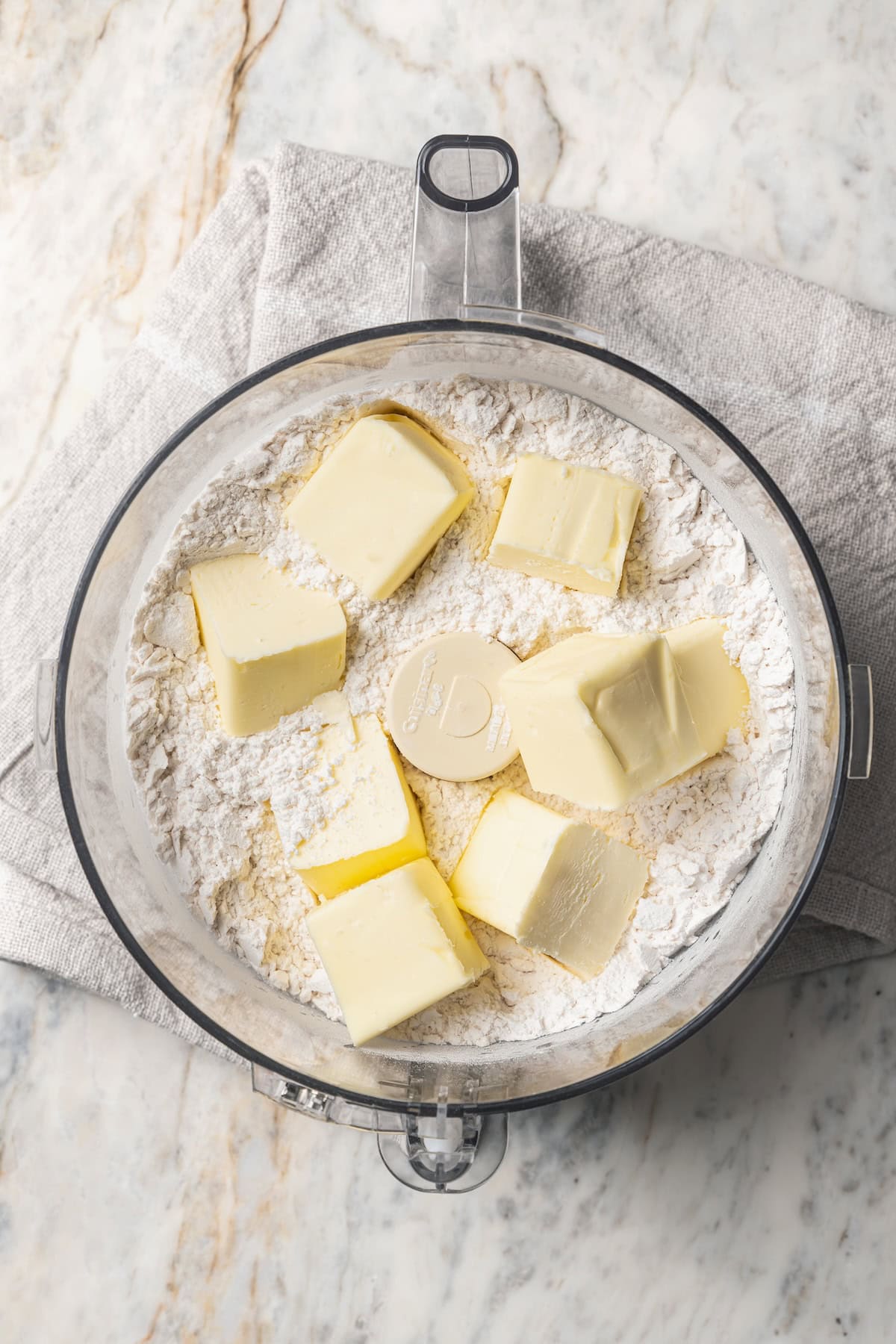 This is the best cherry pie recipe with thick, juicy cherry pie filling flavored with a touch of almond, baked in a buttery, flaky pie crust. Cubed butter added to flour and salt inside the food processor.