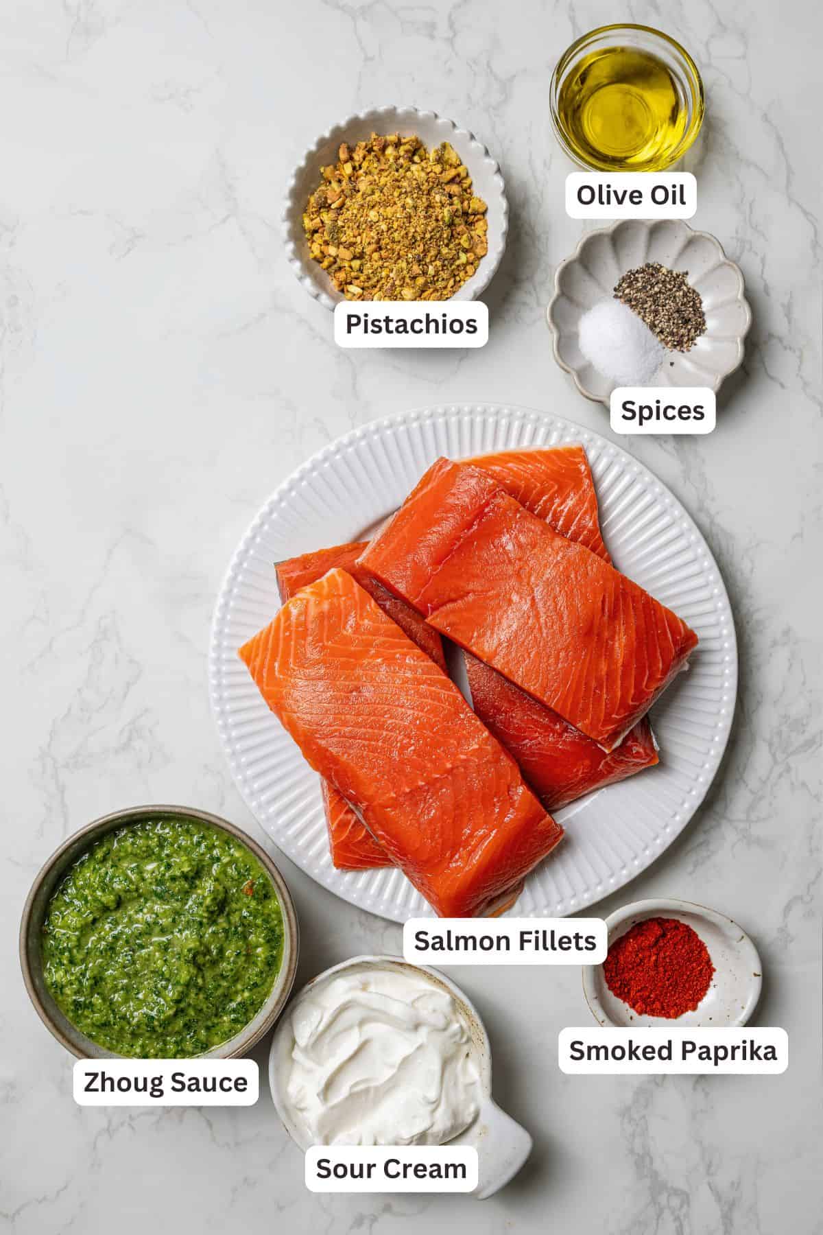 Flaky pistachio-crusted salmon smothered with homemade zhoug sauce and served with a kale salad is a quick, easy dinner packed with flavor! Pistachio crusted salmon ingredients with text labels overlaying each ingredient.