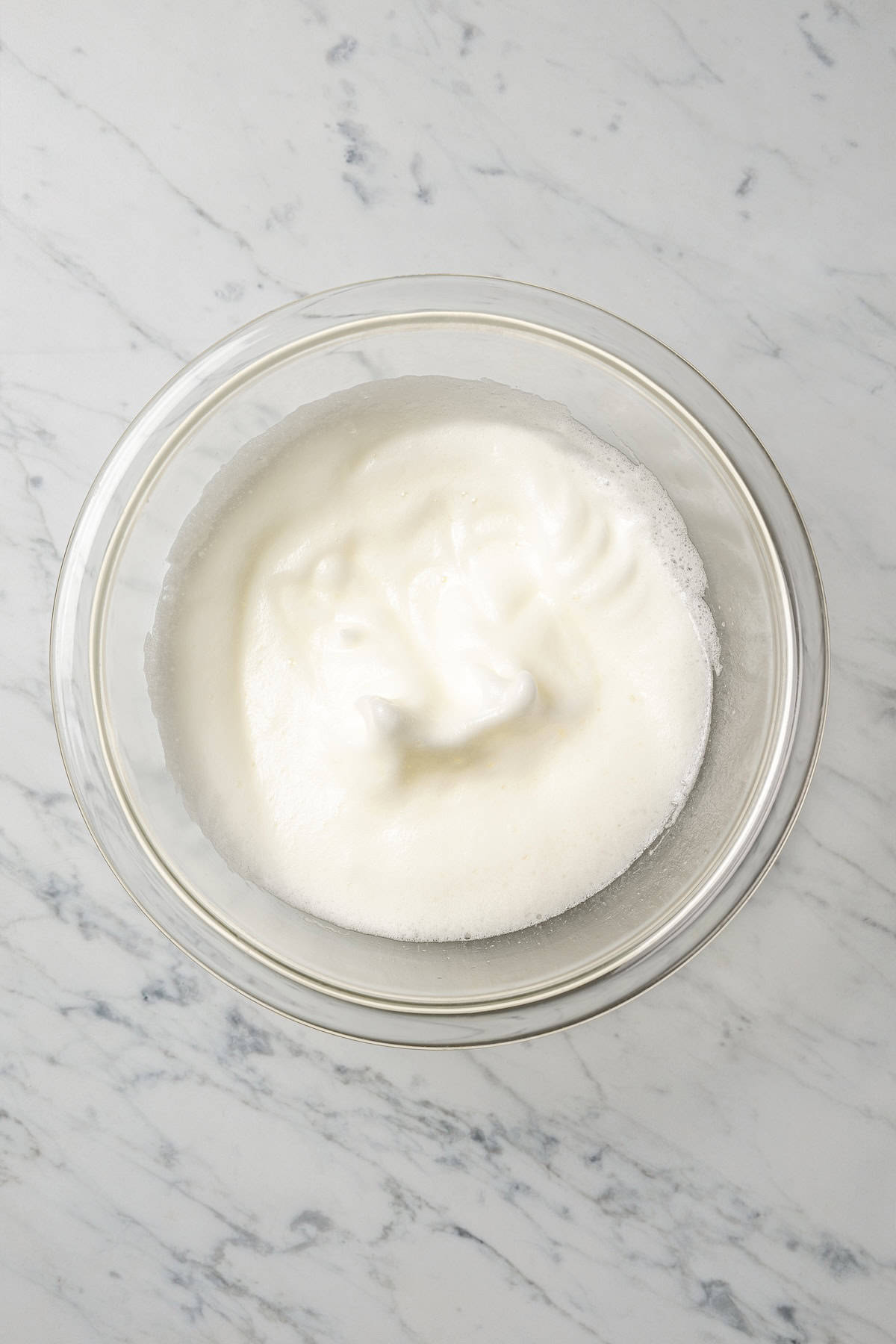 Whipped egg whites in a glass bowl.