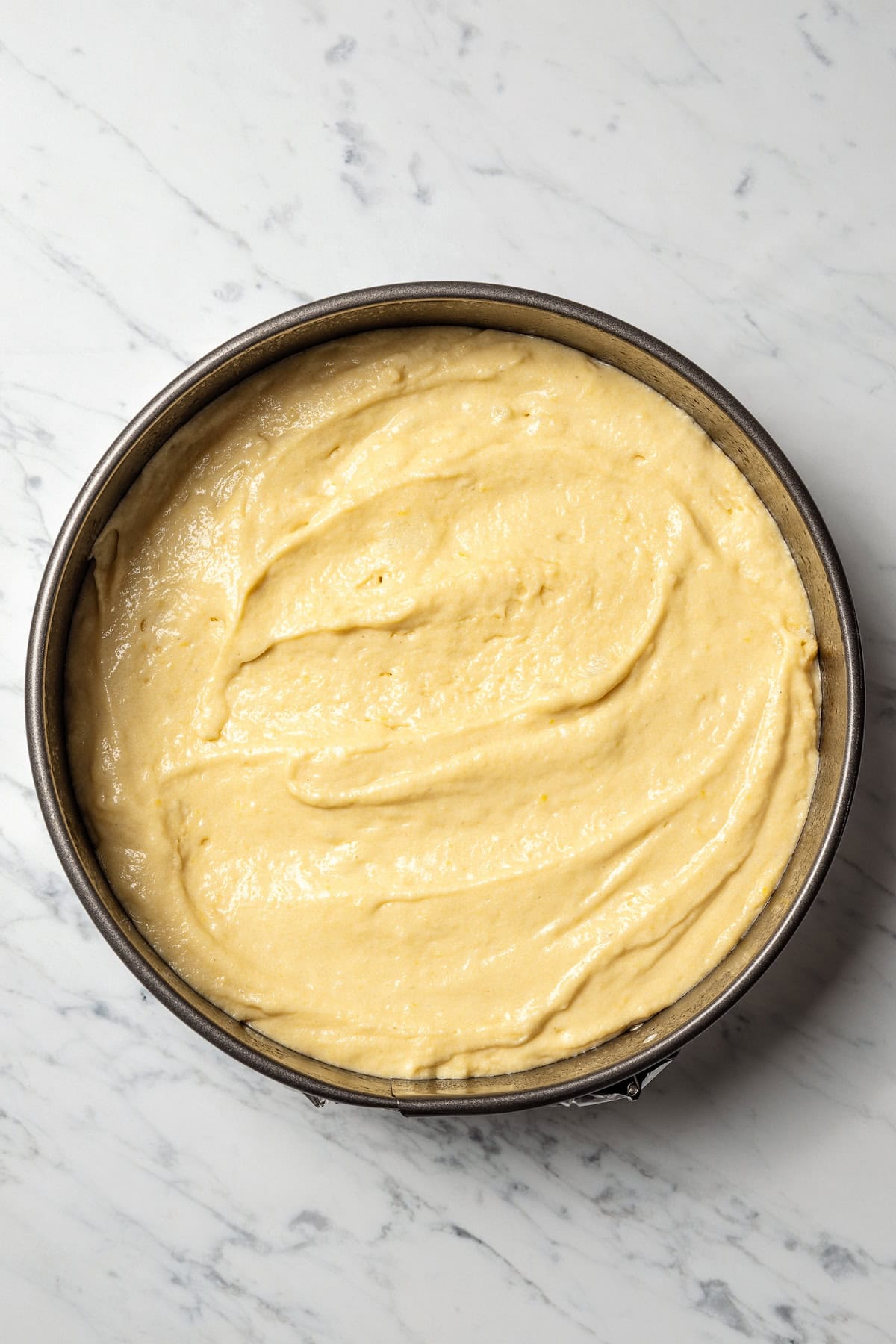 Semolina cake batter spread into a round cake pan.
