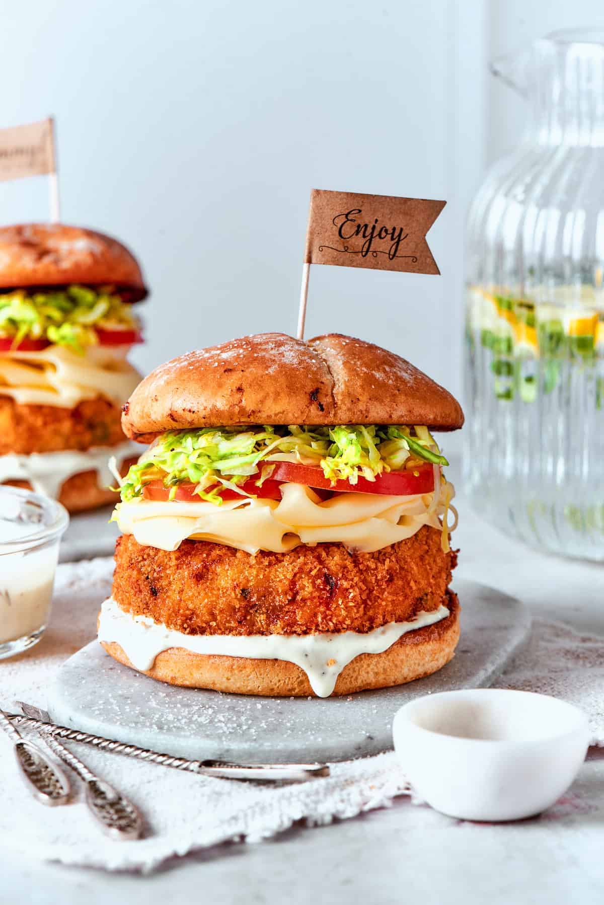 Chicken Bacon Ranch Pizza Shrimp burger piled with cheese and fresh vegetables, and served on a plate.