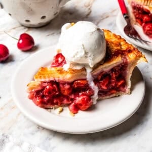 A slice of cherry pie served a la mode with a scoop of ice cream.