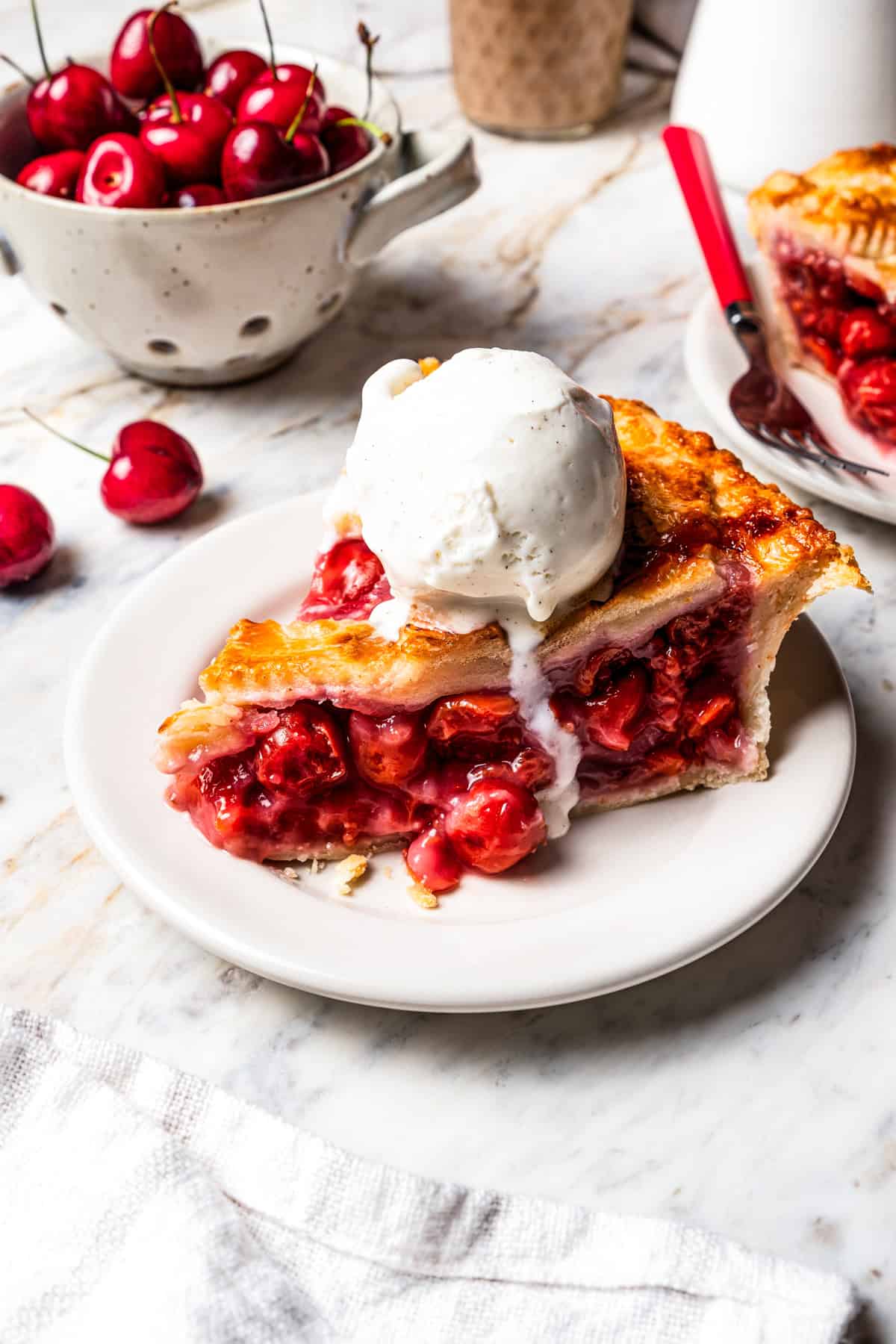 This is the best cherry pie recipe with thick, juicy cherry pie filling flavored with a touch of almond, baked in a buttery, flaky pie crust. A slice of cherry pie served a la mode with a scoop of ice cream.