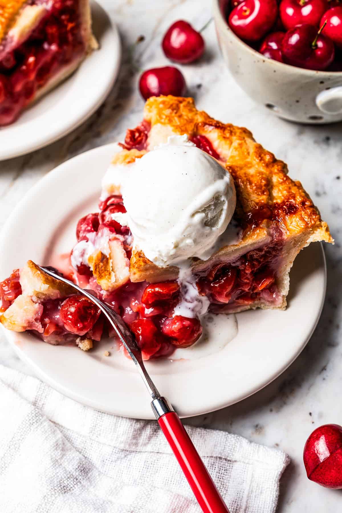 This is the best cherry pie recipe with thick, juicy cherry pie filling flavored with a touch of almond, baked in a buttery, flaky pie crust. A slice of cherry pie served a la mode with a scoop of ice cream.