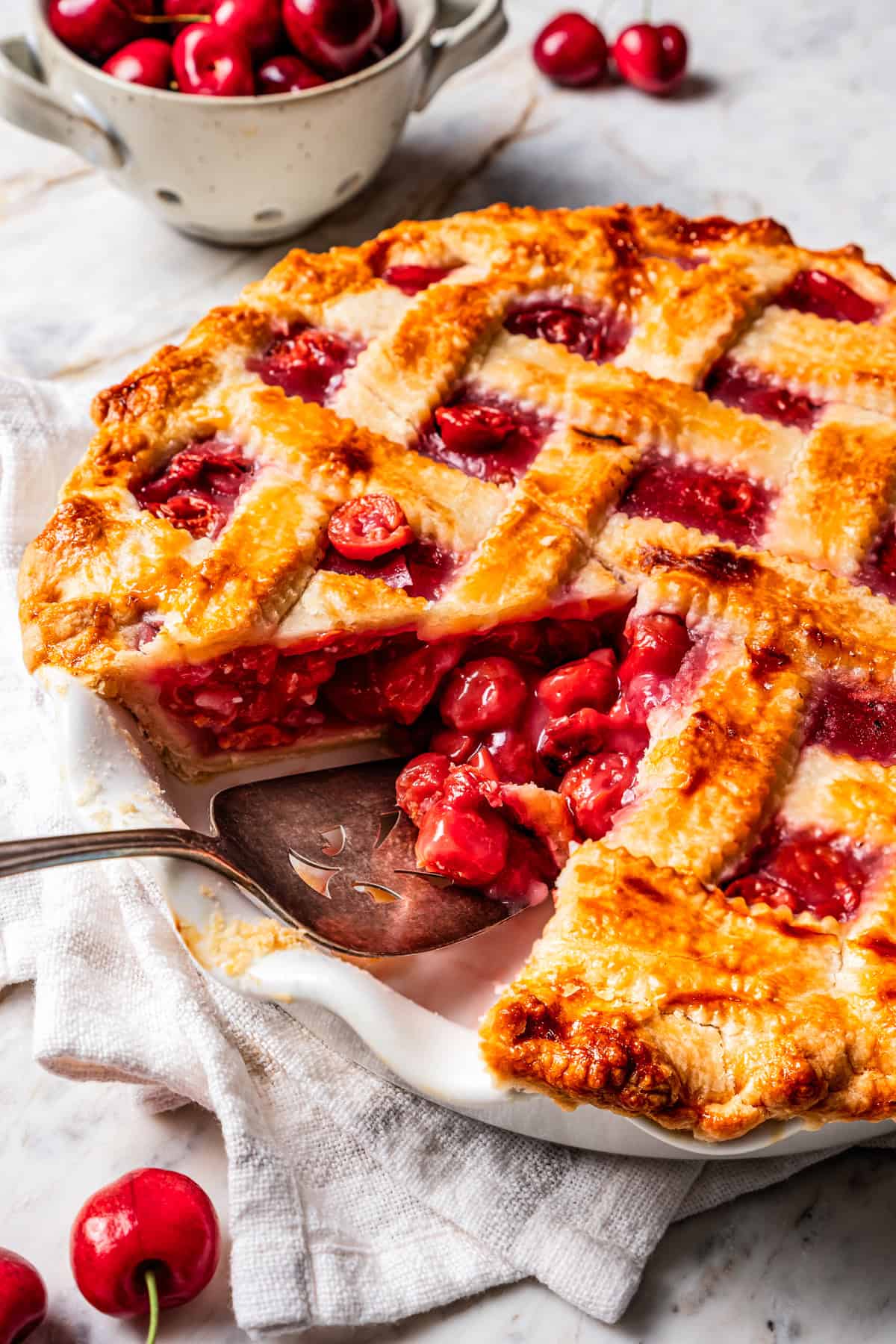This is the best cherry pie recipe with thick, juicy cherry pie filling flavored with a touch of almond, baked in a buttery, flaky pie crust. A cake server resting in a pie dish with a cherry pie.