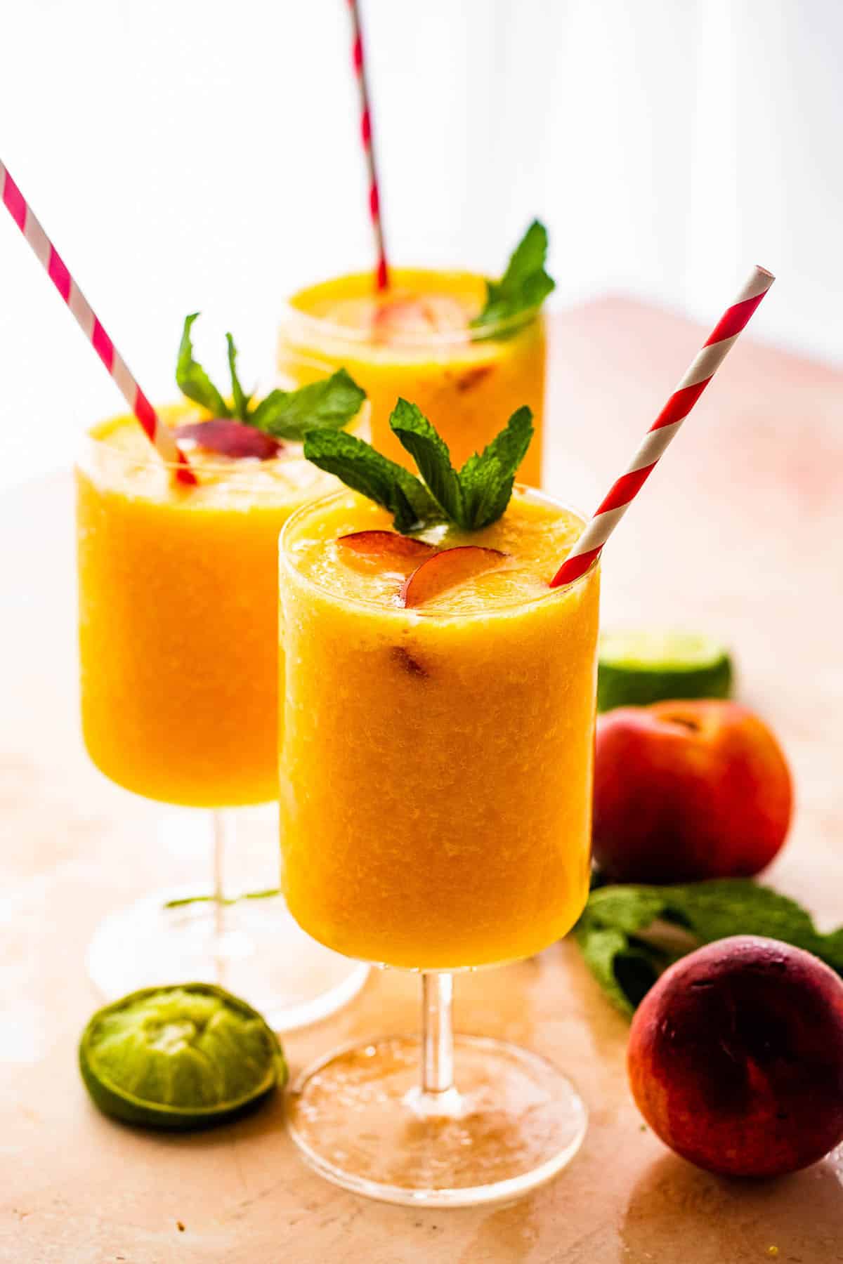 Peach Daiquiri Peach daiquiri served in drinking glasses with straws.