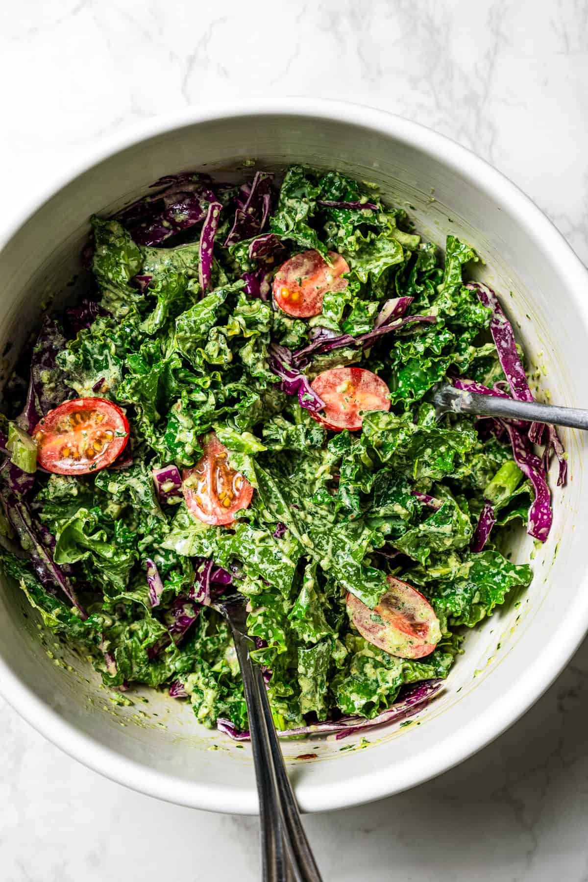Flaky pistachio-crusted salmon smothered with homemade zhoug sauce and served with a kale salad is a quick, easy dinner packed with flavor! A bowl of kale salad tossed with creamy zhoug dressing.