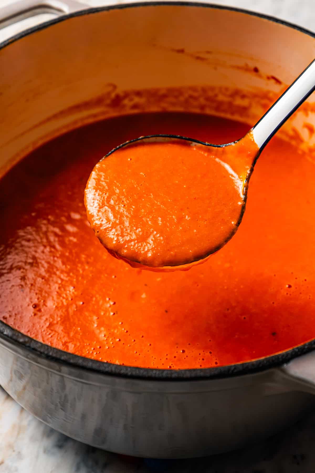 A ladle spooning out tomato soup from the pot. Recipe from diethood.com