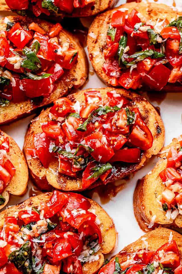 A plate of bread slices topped with a tomato salad to make bruschetta.