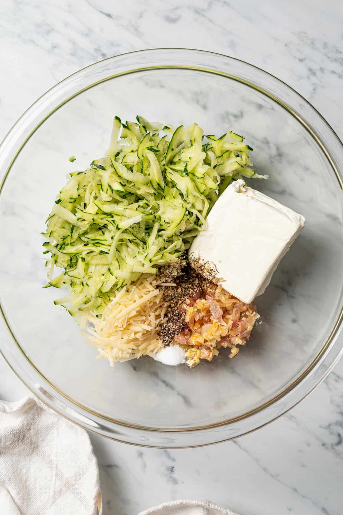 This stuffed chicken breasts recipe has a zesty Italian-inspired filling of fresh zucchini, tomatoes, and creamy cheeses, baked to perfection! Shredded zucchini combined with the filling ingredients in a bowl.